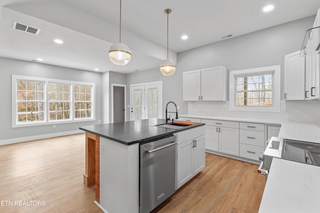 kitchen with pendant lighting, white cabinetry, sink, stainless steel appliances, and a center island with sink