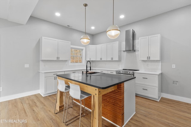 kitchen featuring sink, a breakfast bar area, white cabinetry, stainless steel electric stove, and wall chimney range hood