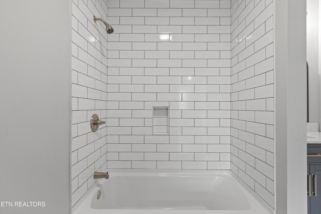 bathroom featuring tiled shower / bath and vanity