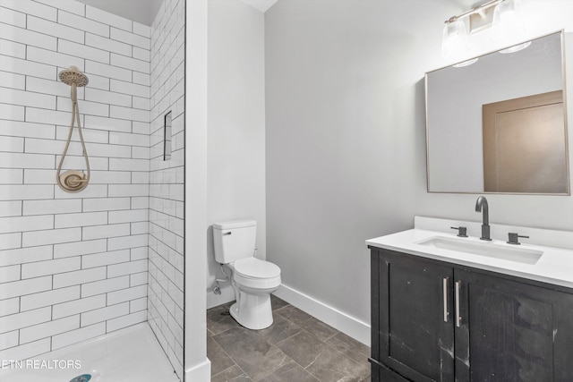 bathroom with vanity, toilet, and tiled shower