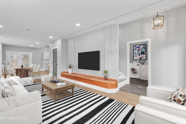 living room with separate washer and dryer, wood-type flooring, and an inviting chandelier