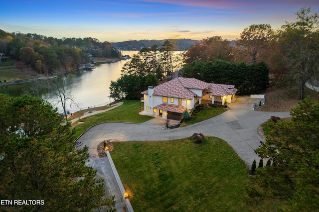 aerial view at dusk featuring a water view