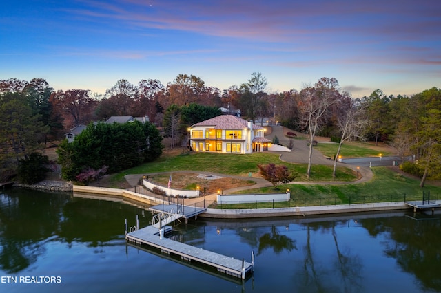 back house at dusk featuring a yard and a water view