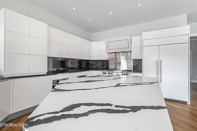 kitchen with paneled refrigerator, dark hardwood / wood-style floors, a kitchen island, and white cabinetry