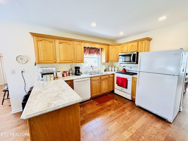 kitchen with light wood-type flooring, white appliances, and sink