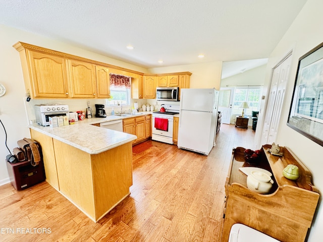 kitchen with kitchen peninsula, white appliances, light hardwood / wood-style flooring, and a wealth of natural light