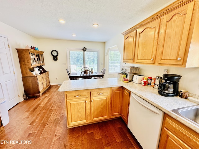 kitchen featuring sink, dark hardwood / wood-style floors, kitchen peninsula, white dishwasher, and a textured ceiling