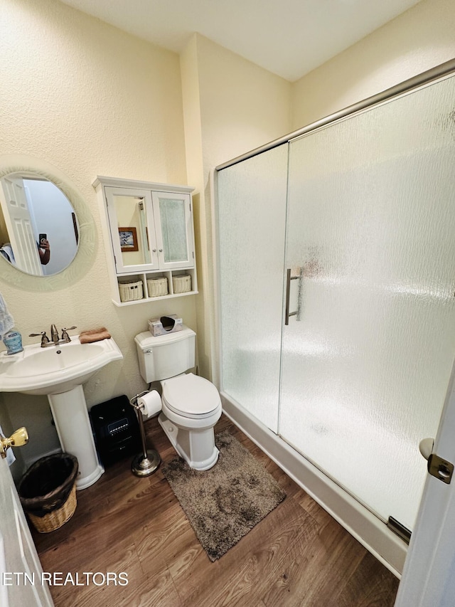 bathroom featuring toilet, sink, hardwood / wood-style floors, and walk in shower