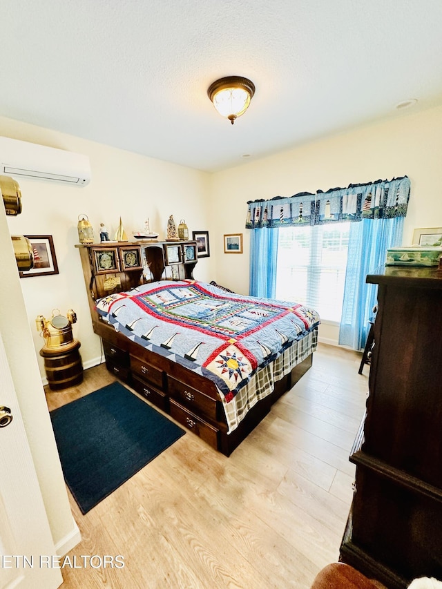 bedroom with light hardwood / wood-style flooring and a wall mounted AC