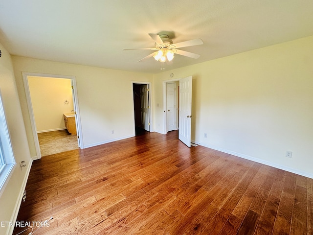 813 Clear Creek Pkwy, Clarkrange, TN 38553 - unfurnished bedroom featuring wood finished floors, baseboards, ensuite bath, and a ceiling fan