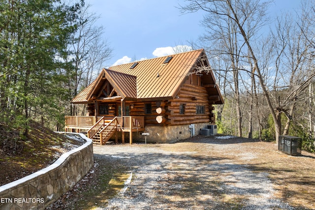 log home with gravel driveway, a standing seam roof, central AC, metal roof, and log siding