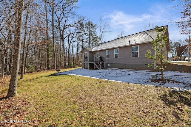 back of property featuring a deck and a lawn