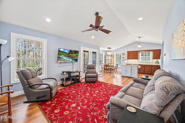 living room featuring light wood-type flooring, a healthy amount of sunlight, lofted ceiling, and ceiling fan