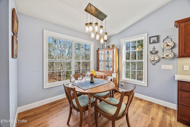 dining room featuring a chandelier, lofted ceiling, and light hardwood / wood-style flooring