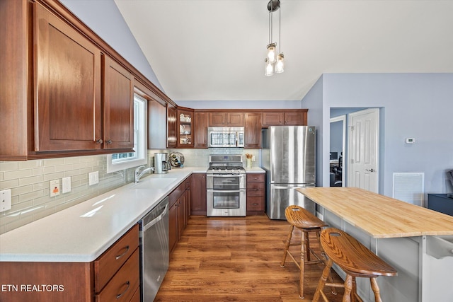 kitchen featuring decorative light fixtures, sink, appliances with stainless steel finishes, and a breakfast bar