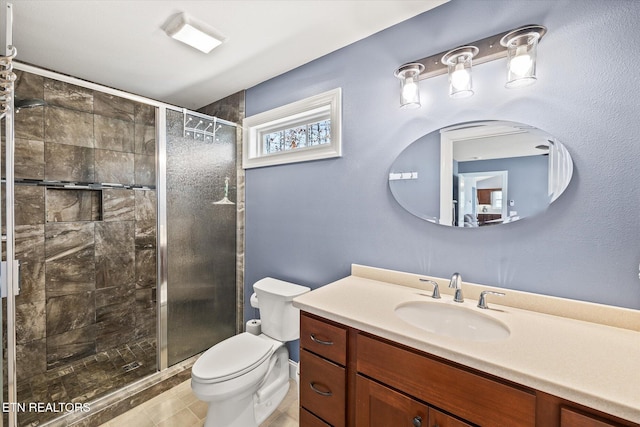 bathroom with vanity, toilet, tile patterned flooring, and a shower with door