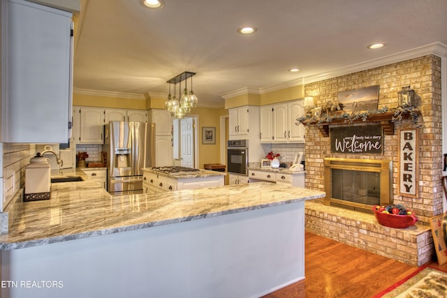 105 Charity Ln, Jamestown, TN 38556 - kitchen featuring appliances with stainless steel finishes, ornamental molding, a sink, light stone countertops, and a peninsula