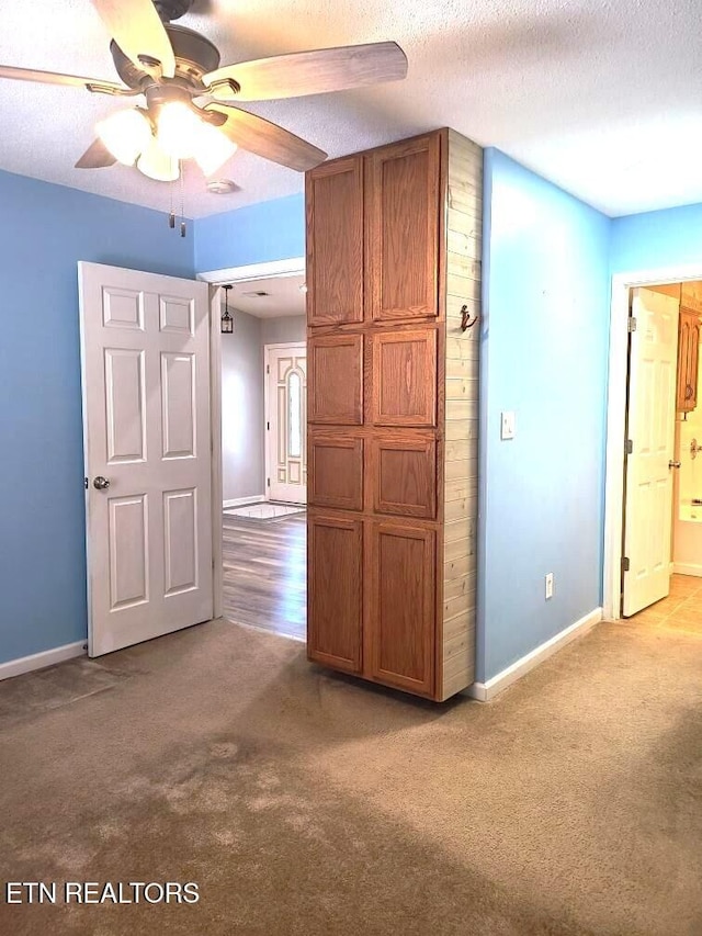 carpeted spare room with ceiling fan and a textured ceiling