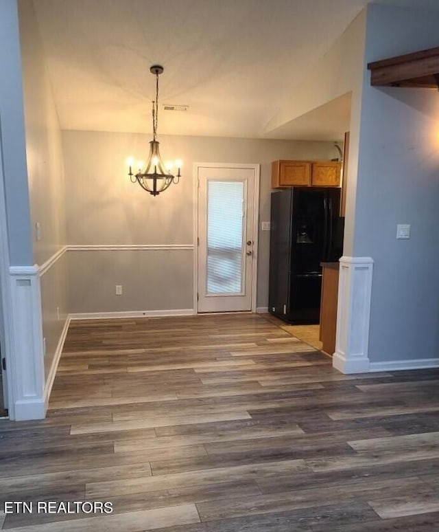 unfurnished dining area with dark hardwood / wood-style floors and an inviting chandelier