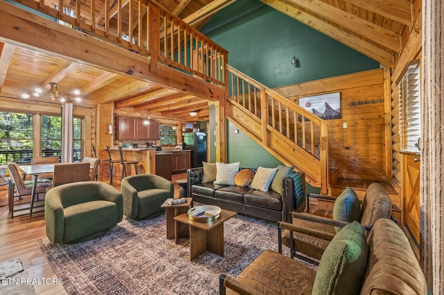 living room with beam ceiling, light wood-type flooring, wooden ceiling, and high vaulted ceiling