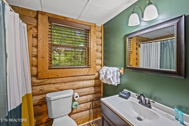 bathroom featuring rustic walls, vanity, and toilet