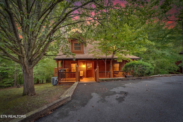 log-style house with central AC unit and a porch