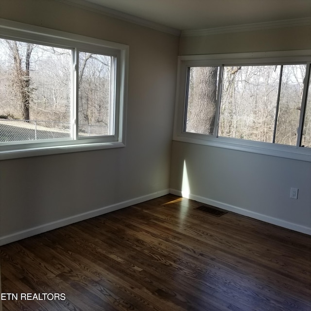 empty room with dark hardwood / wood-style flooring and crown molding