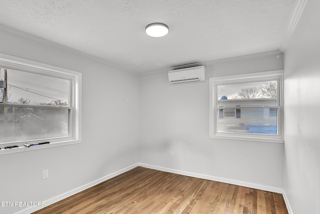 spare room with crown molding, hardwood / wood-style floors, a textured ceiling, and a wall unit AC