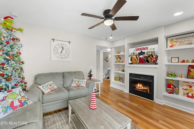 living room with hardwood / wood-style flooring, ceiling fan, and built in features