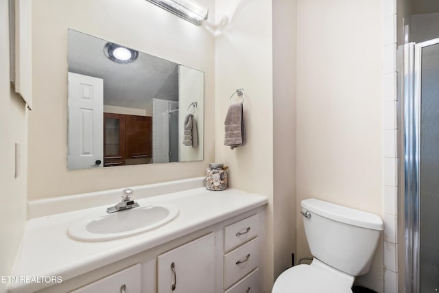 bathroom featuring toilet, a textured ceiling, a shower with door, and vanity