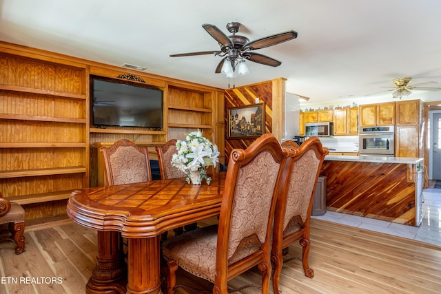 dining space featuring built in shelves, ceiling fan, and light hardwood / wood-style flooring