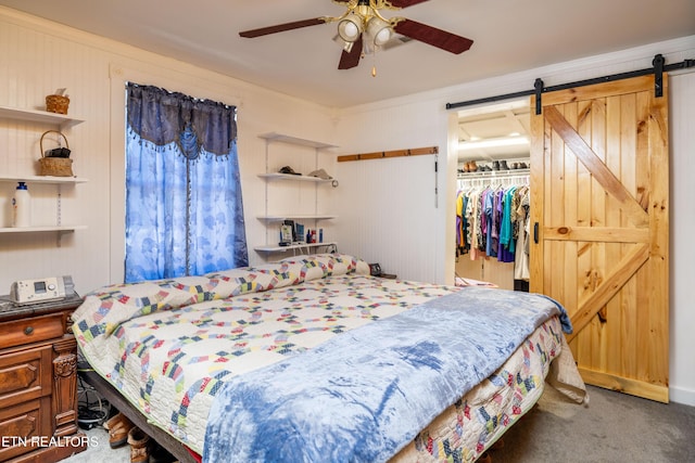 bedroom with dark carpet, ceiling fan, crown molding, a barn door, and a closet