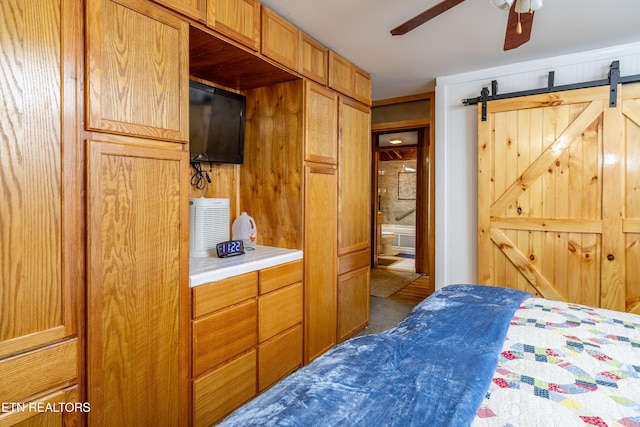 bedroom with connected bathroom, a barn door, and ceiling fan