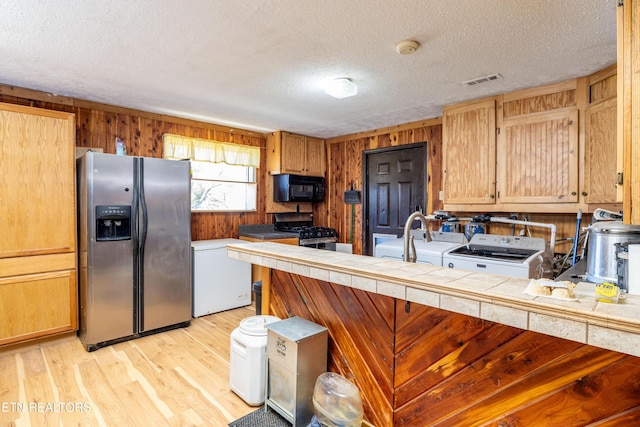 kitchen with sink, tile countertops, washer / clothes dryer, a textured ceiling, and appliances with stainless steel finishes