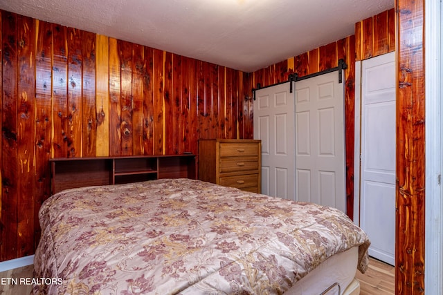 bedroom featuring a barn door and wooden walls