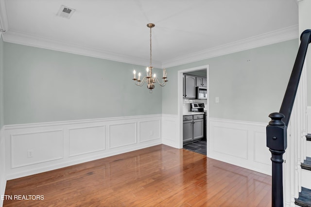 unfurnished dining area with dark hardwood / wood-style flooring, an inviting chandelier, and crown molding