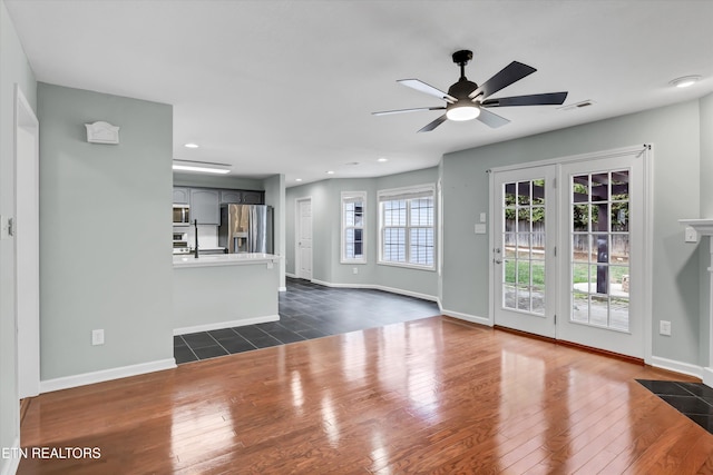 unfurnished living room featuring ceiling fan and dark wood-type flooring