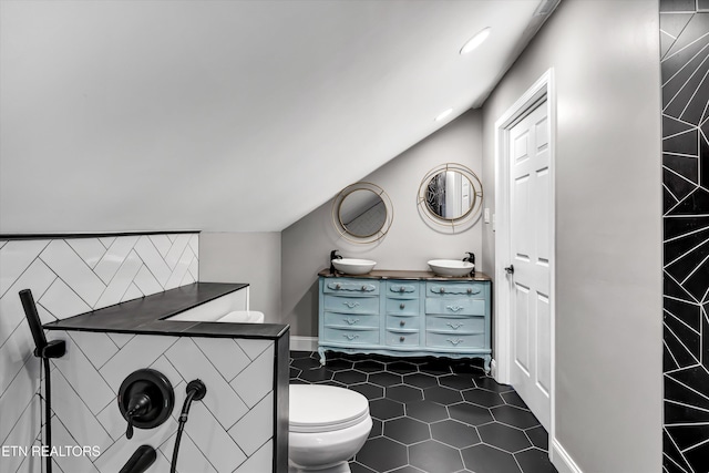 bathroom featuring tile patterned flooring, vanity, vaulted ceiling, and toilet