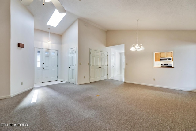 carpeted entrance foyer with a skylight, high vaulted ceiling, and ceiling fan with notable chandelier