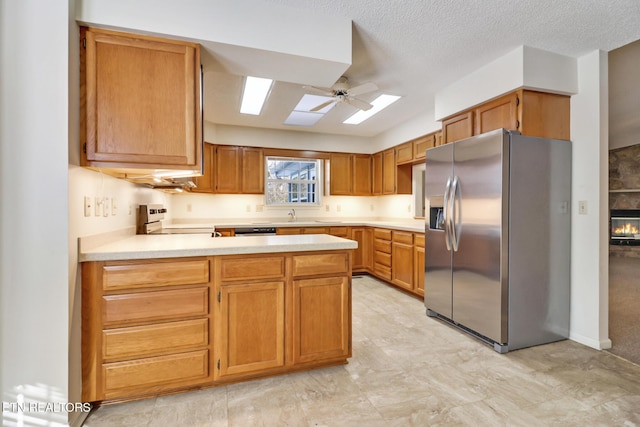 kitchen with ceiling fan, stainless steel fridge with ice dispenser, kitchen peninsula, a textured ceiling, and range