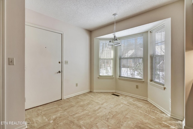 unfurnished dining area with a textured ceiling, an inviting chandelier, and plenty of natural light