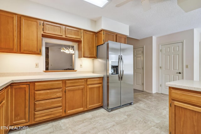 kitchen featuring stainless steel refrigerator with ice dispenser, ceiling fan with notable chandelier, and a textured ceiling