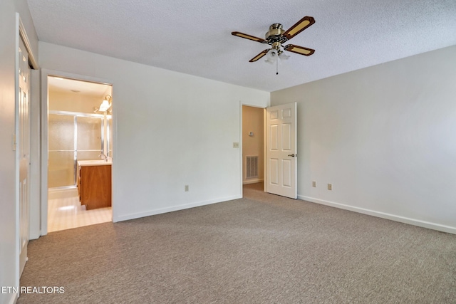 unfurnished bedroom with carpet flooring, ceiling fan, a textured ceiling, and connected bathroom