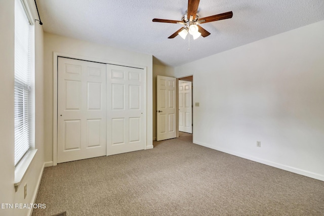 unfurnished bedroom featuring ceiling fan, a closet, carpet, and a textured ceiling