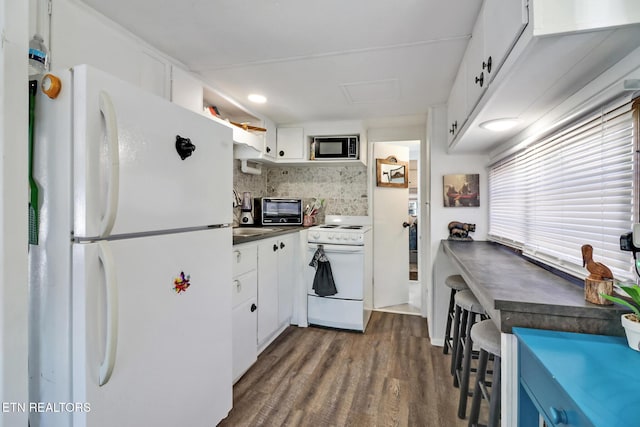 kitchen featuring white appliances, dark wood finished floors, white cabinetry, dark countertops, and backsplash
