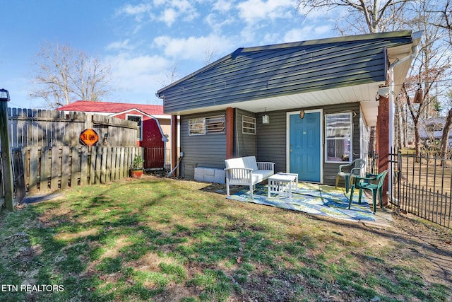 rear view of property featuring a patio area, a yard, and a fenced backyard