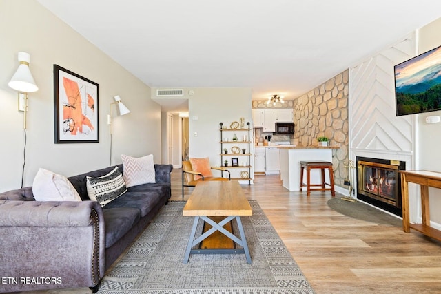 living room with a large fireplace and light hardwood / wood-style floors