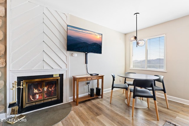 dining room featuring hardwood / wood-style floors and a large fireplace