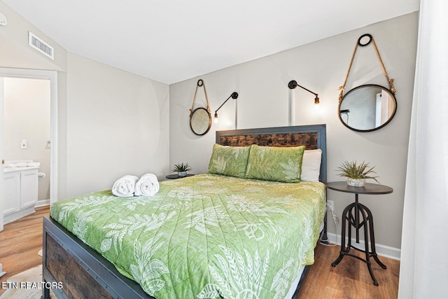 bedroom with ensuite bathroom and hardwood / wood-style floors