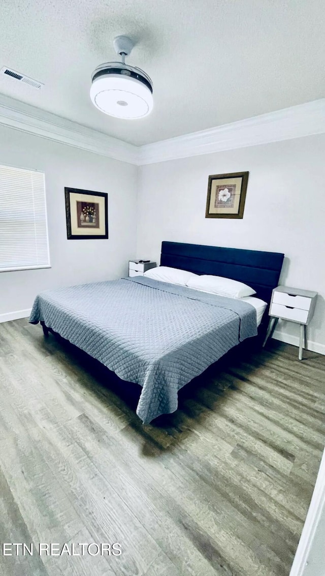 bedroom with hardwood / wood-style flooring, ornamental molding, and a textured ceiling